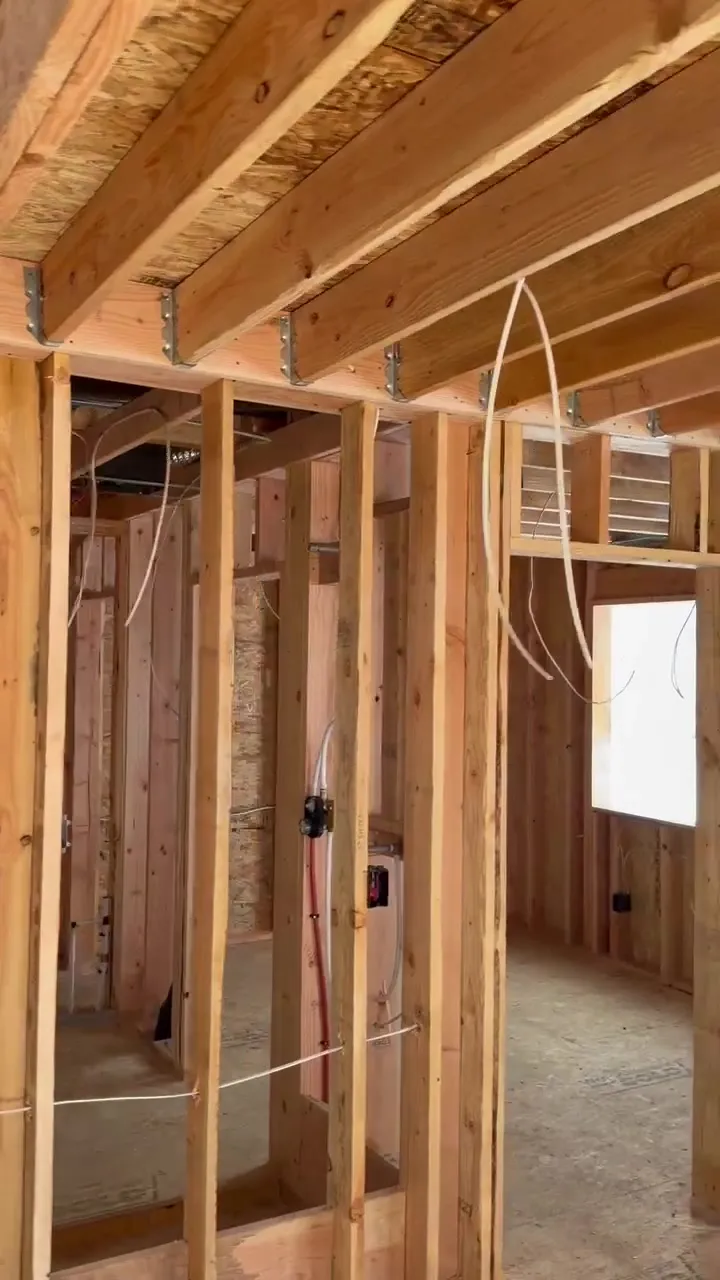 Interior framing of a new ADU near Kalama WA with NM cable runs looping down from the ceiling joists, device boxes on the studs and a window opening on the right