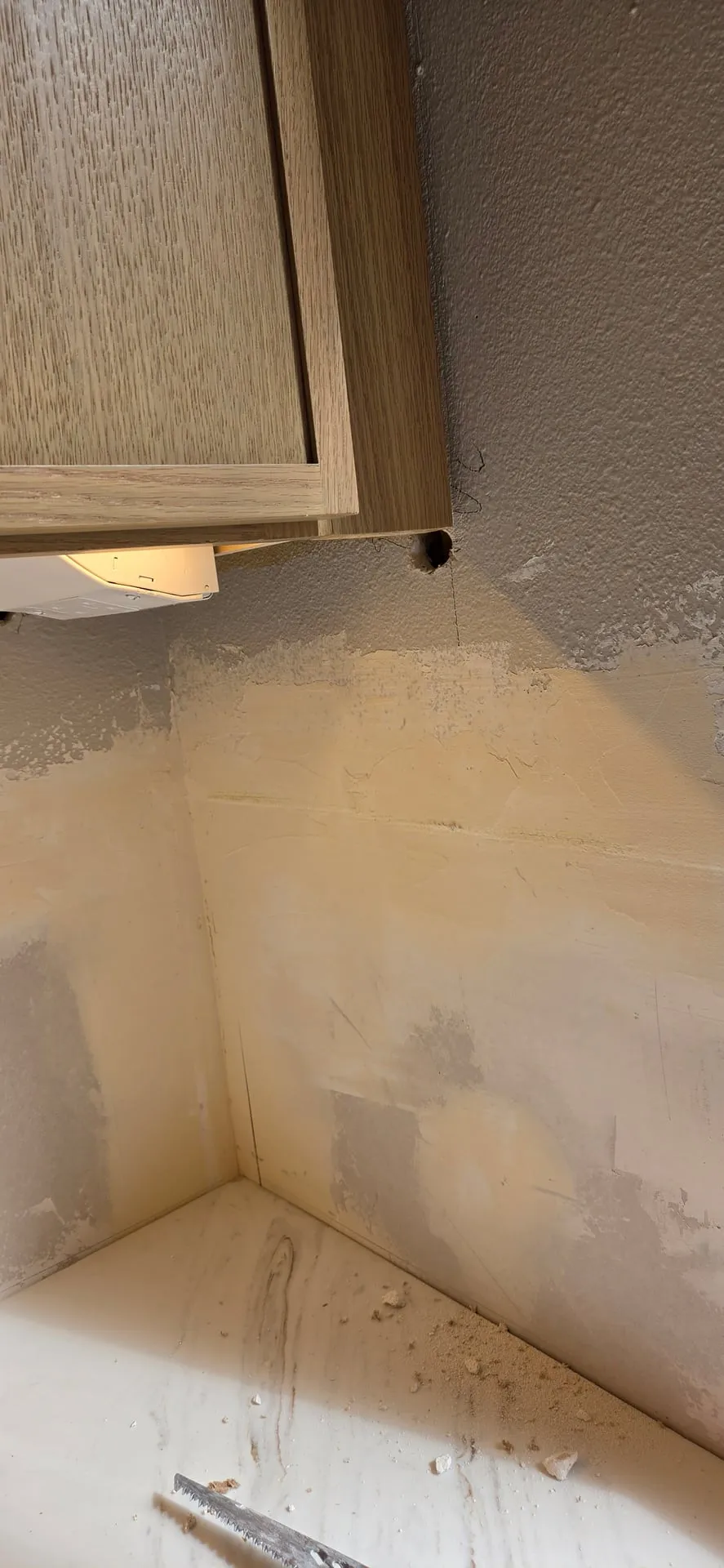 Underside of an upper cabinet in a Ridgefield WA kitchen with the exposed cable gone and the wall below patched and ready for a backsplash