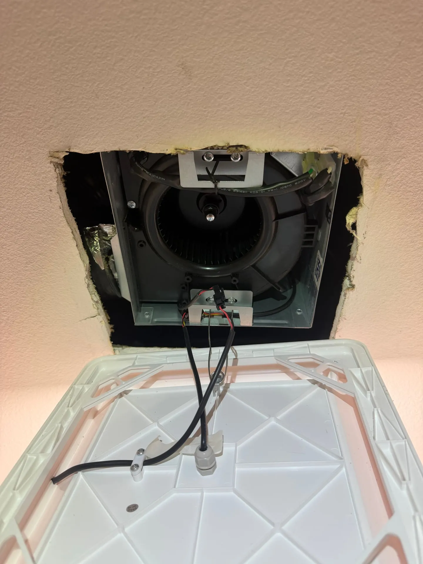 Bath exhaust fan housing being installed into a ceiling opening in a Brush Prairie WA home, with the wiring connections made at the fan body