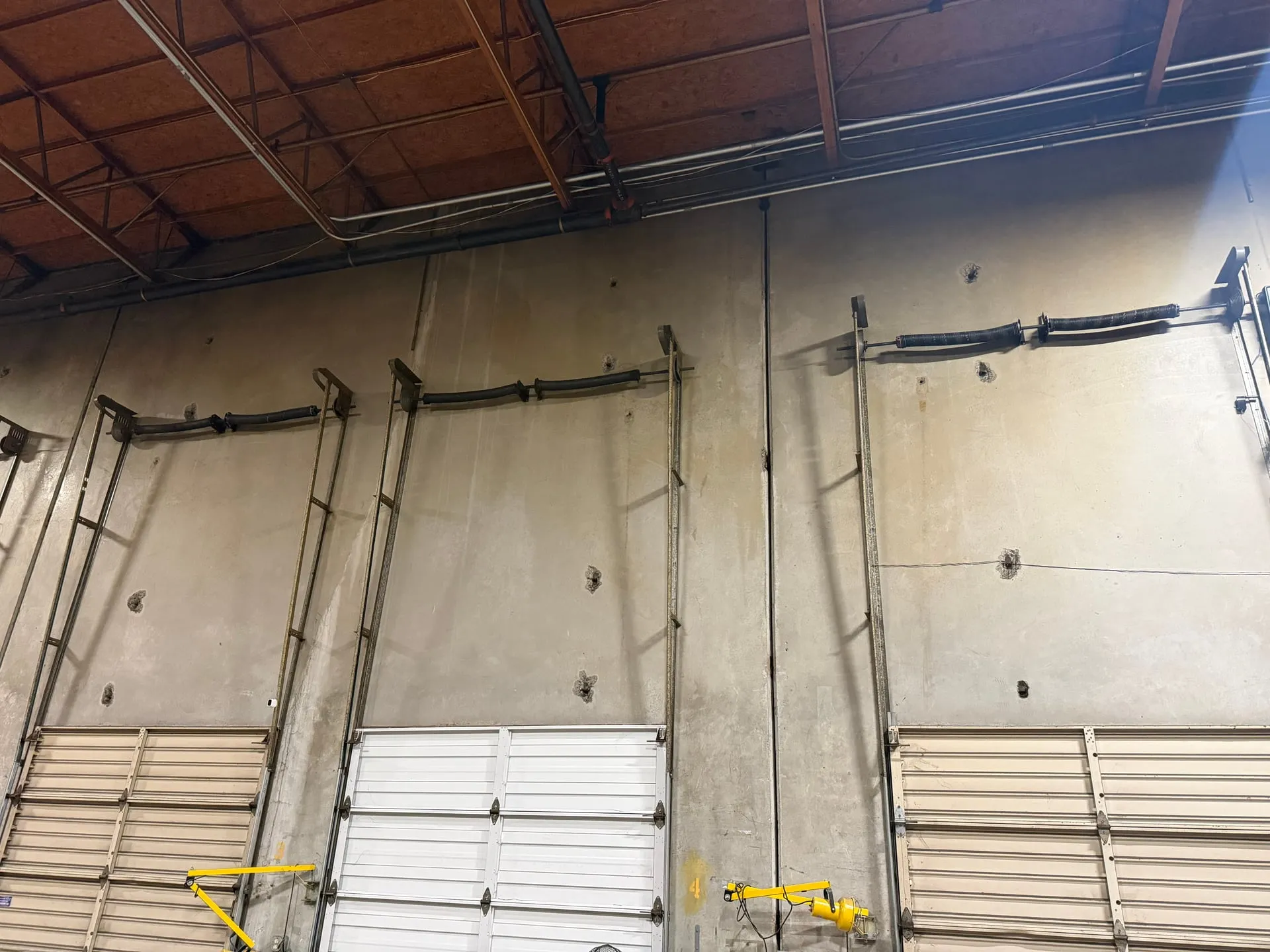 Bare tilt-up concrete warehouse wall in Vancouver WA before the machine circuits were installed, with loading doors and nothing but the existing conduit on the wall