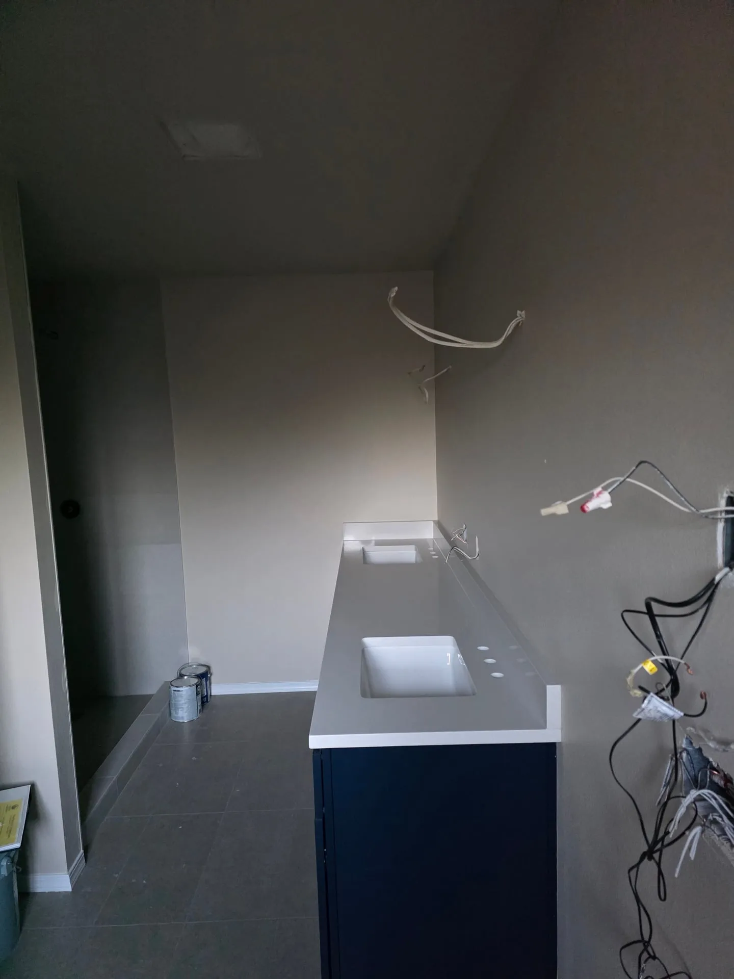 Bathroom in a Vancouver WA addition before electrical trim with wires hanging out of the wall above a new vanity