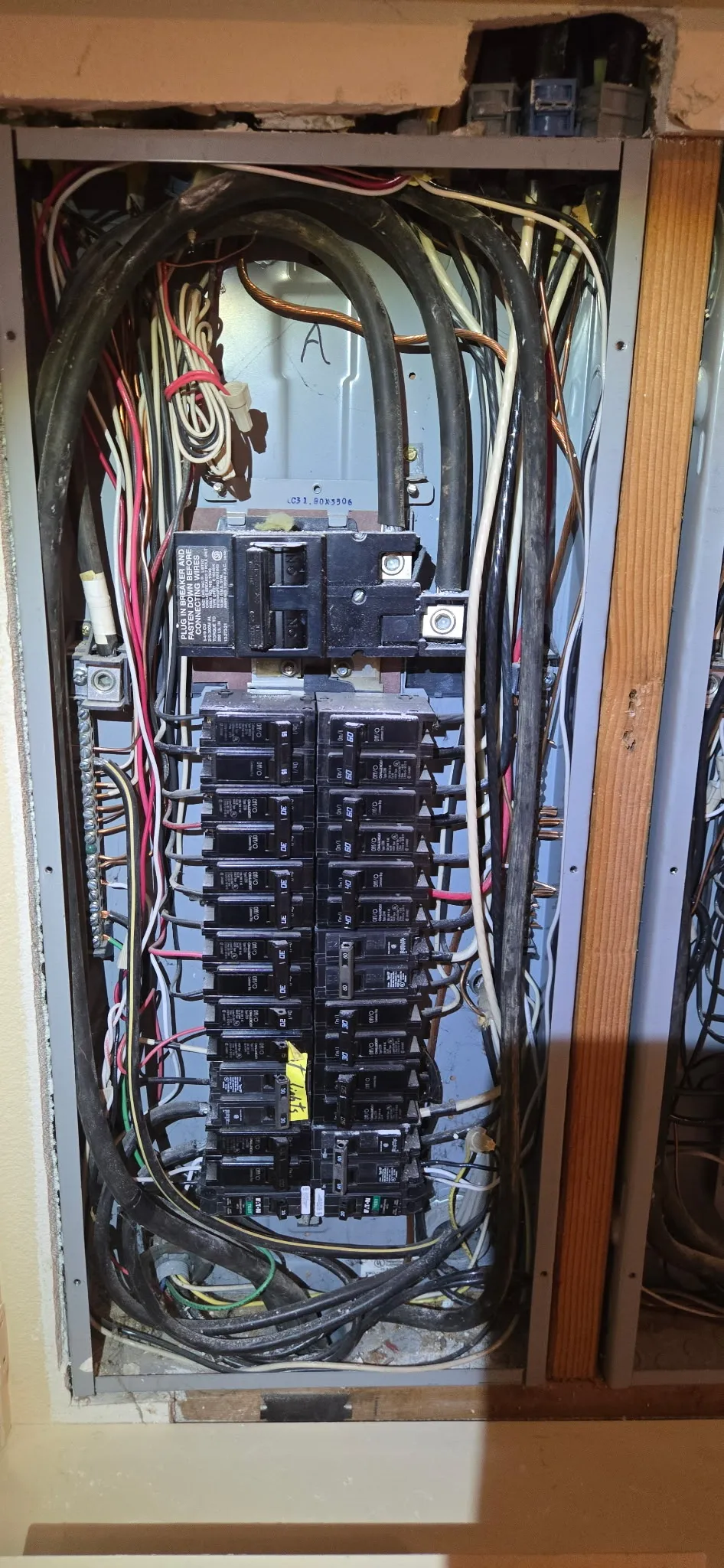 Electrical panel in a Brush Prairie WA home before correction, showing breakers with two conductors landed under a single lug and loose wiring across the bus