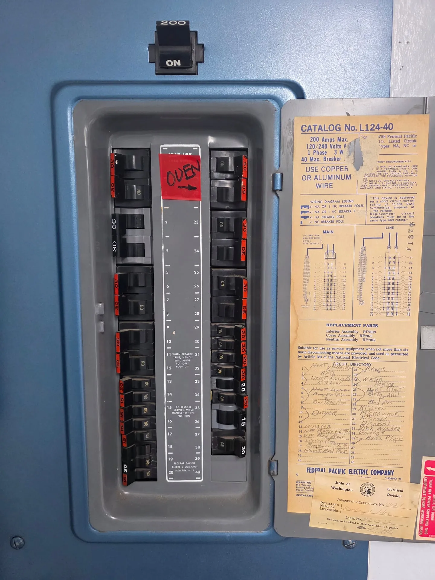 Original Federal Pacific Electric Company load center in a Washougal WA home before replacement, with the yellowed catalog label reading Catalog No. L124-40 and a handwritten OVEN tag on the door