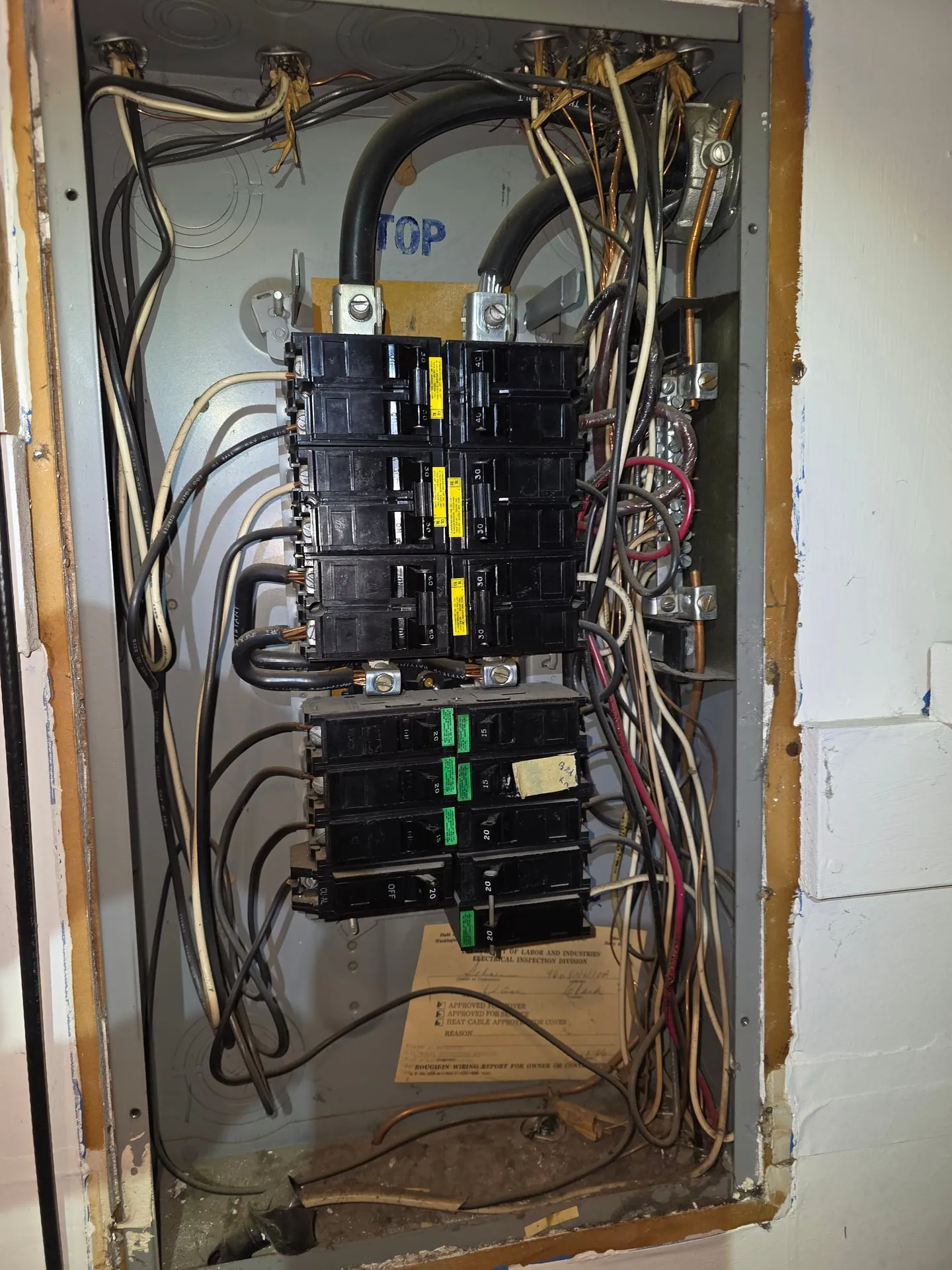 Old electrical panel with the cover off and crowded wiring in a Vancouver WA home before the update