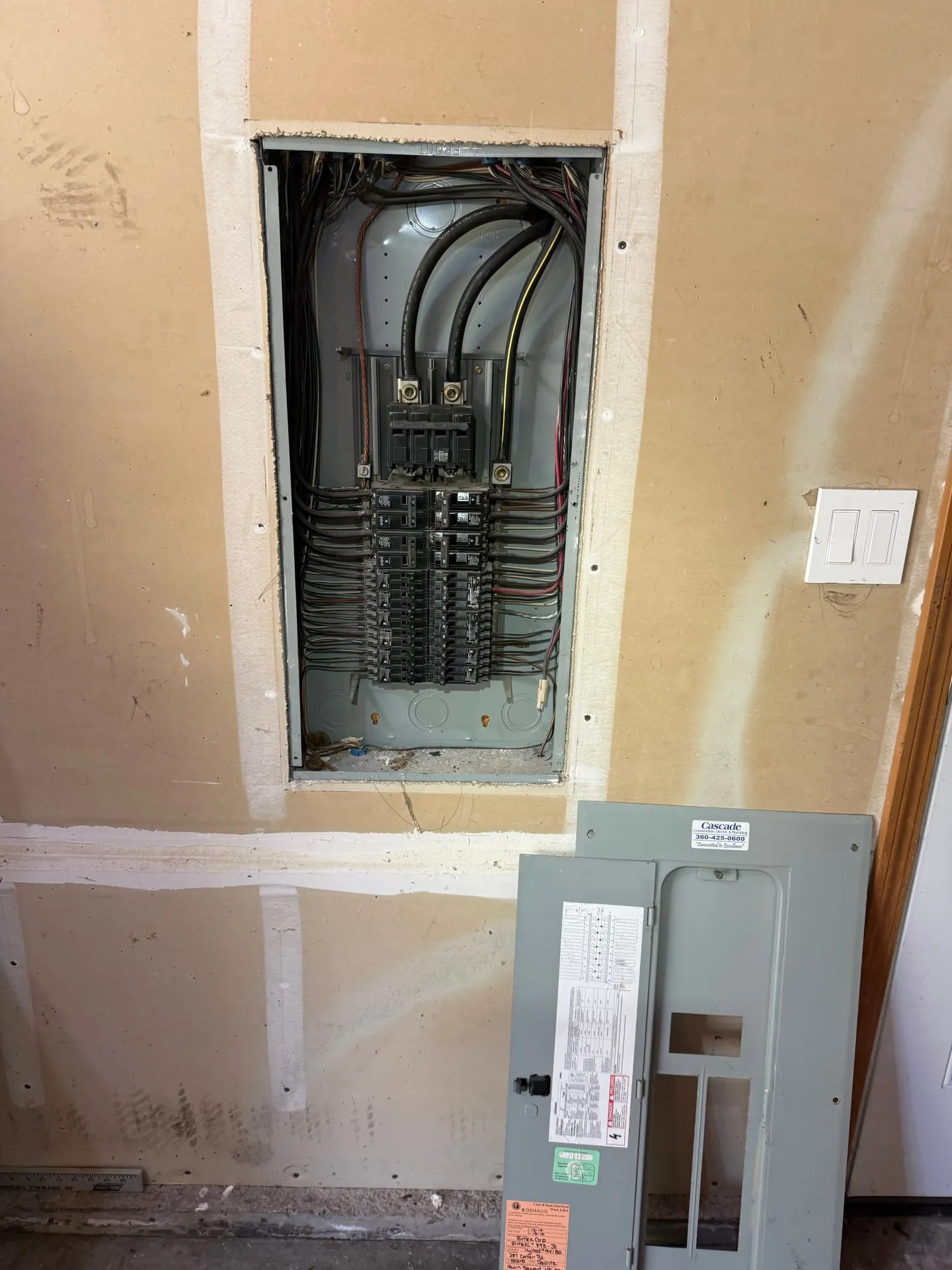 Original electrical panel in a Kalama WA garage before replacement, opened to show crowded branch circuit conductors and aged breakers filling the bus