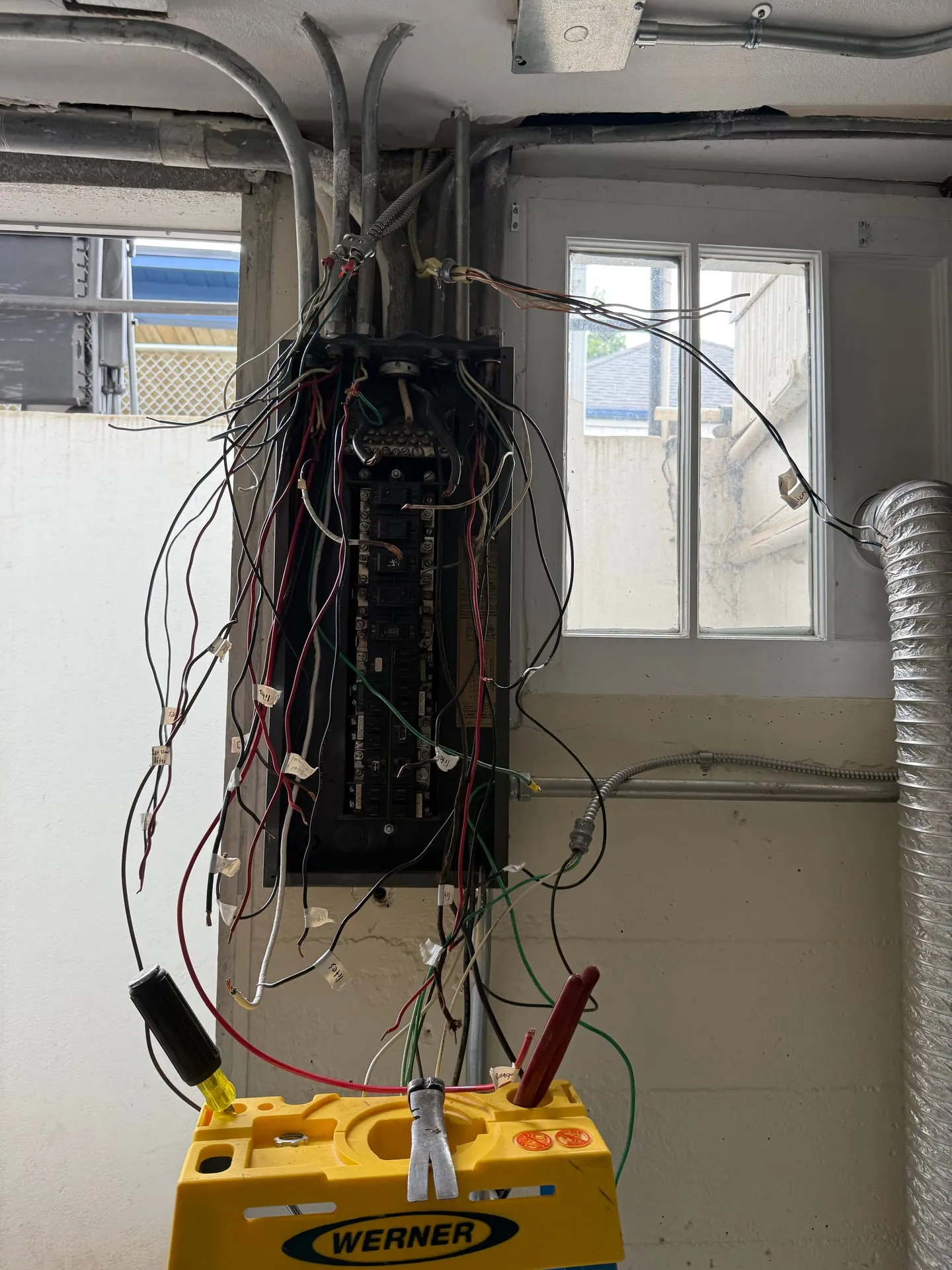 Original electrical panel in an older Vancouver WA home before replacement, with dozens of conductors fanning out of the enclosure in every direction and splices hanging outside the box