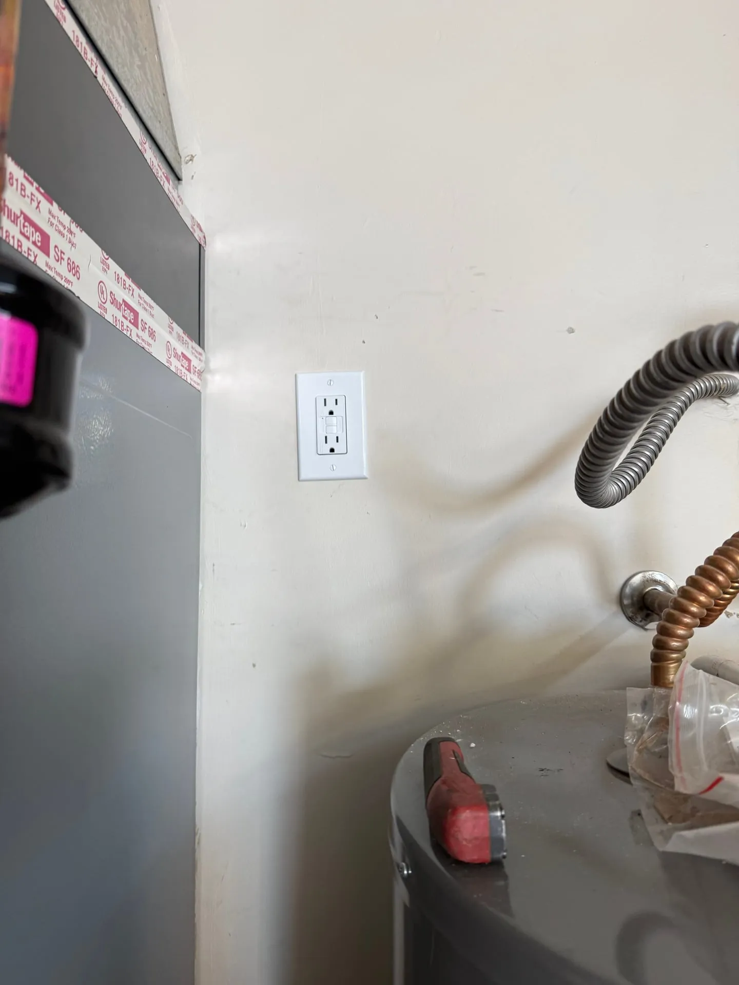 New GFCI receptacle on the wall beside an air handler and water heater in a Vancouver WA home, added to power the HVAC condensate pump