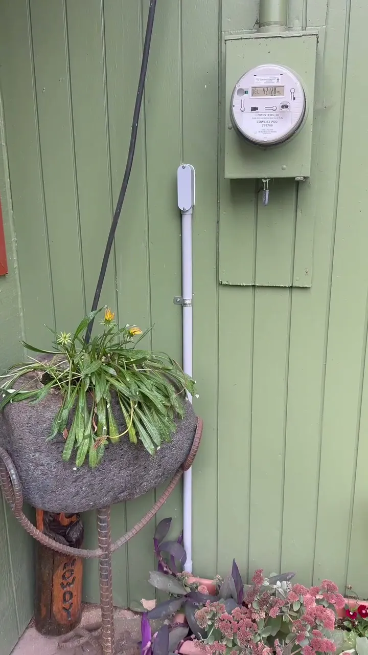 Gray PVC conduit riser running up the green siding of a Kelso WA home beside the electric meter