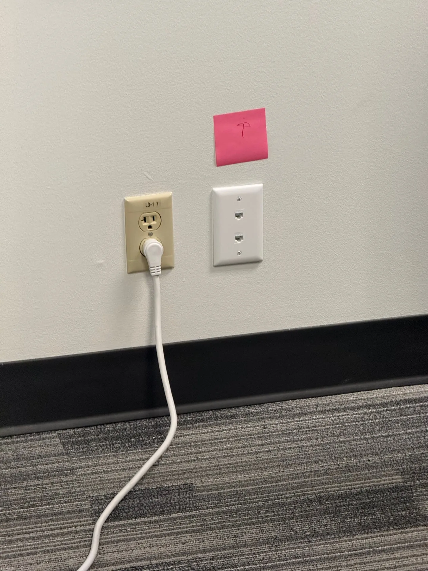 Data jack installed next to a power receptacle on an office wall in Vancouver WA, with the cover plates aligned above the carpet baseboard