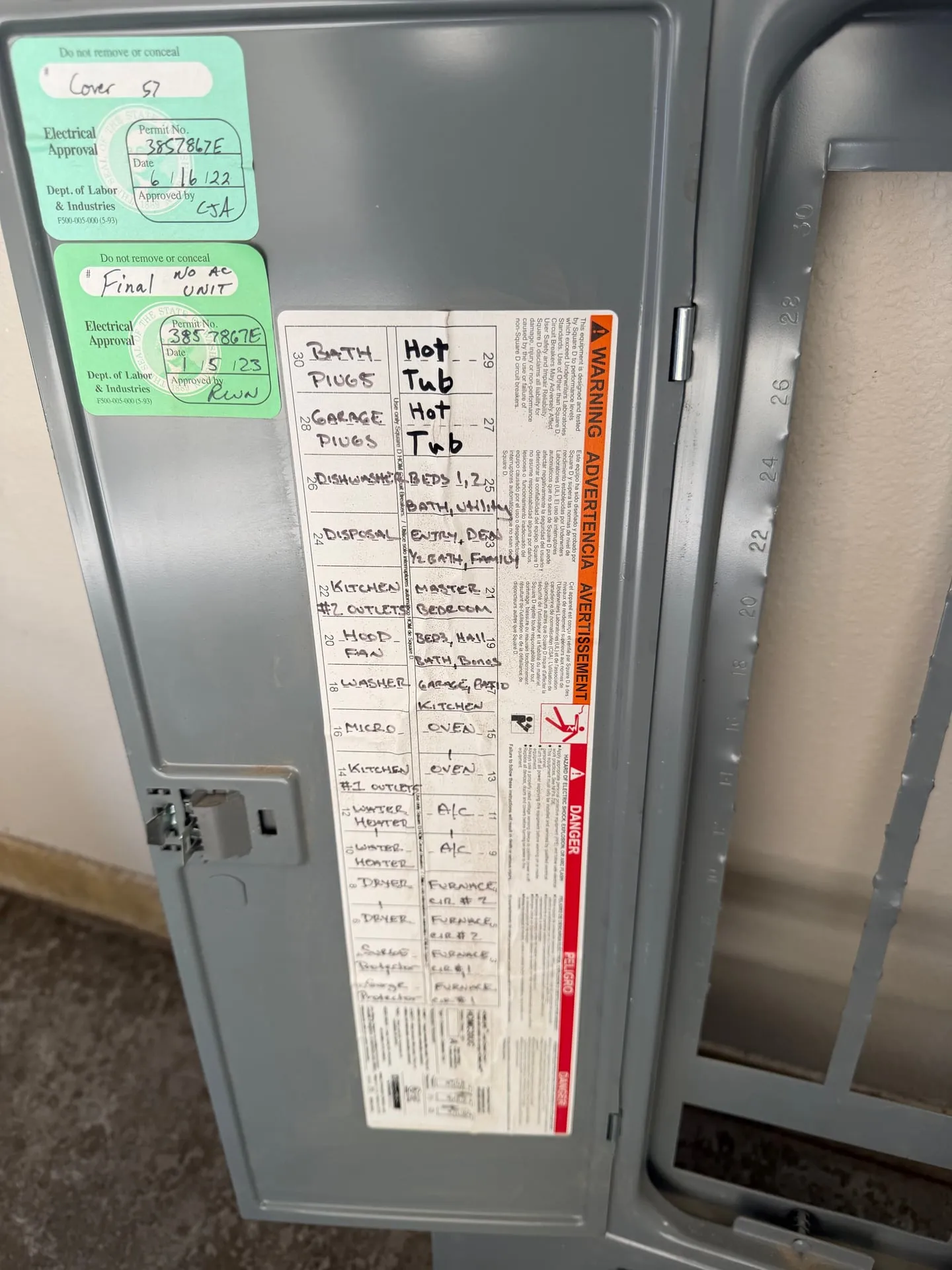 Electrical panel cover in a Vancouver WA home showing the handwritten circuit directory and Washington L&I permit approval stickers from the home's 2022 construction