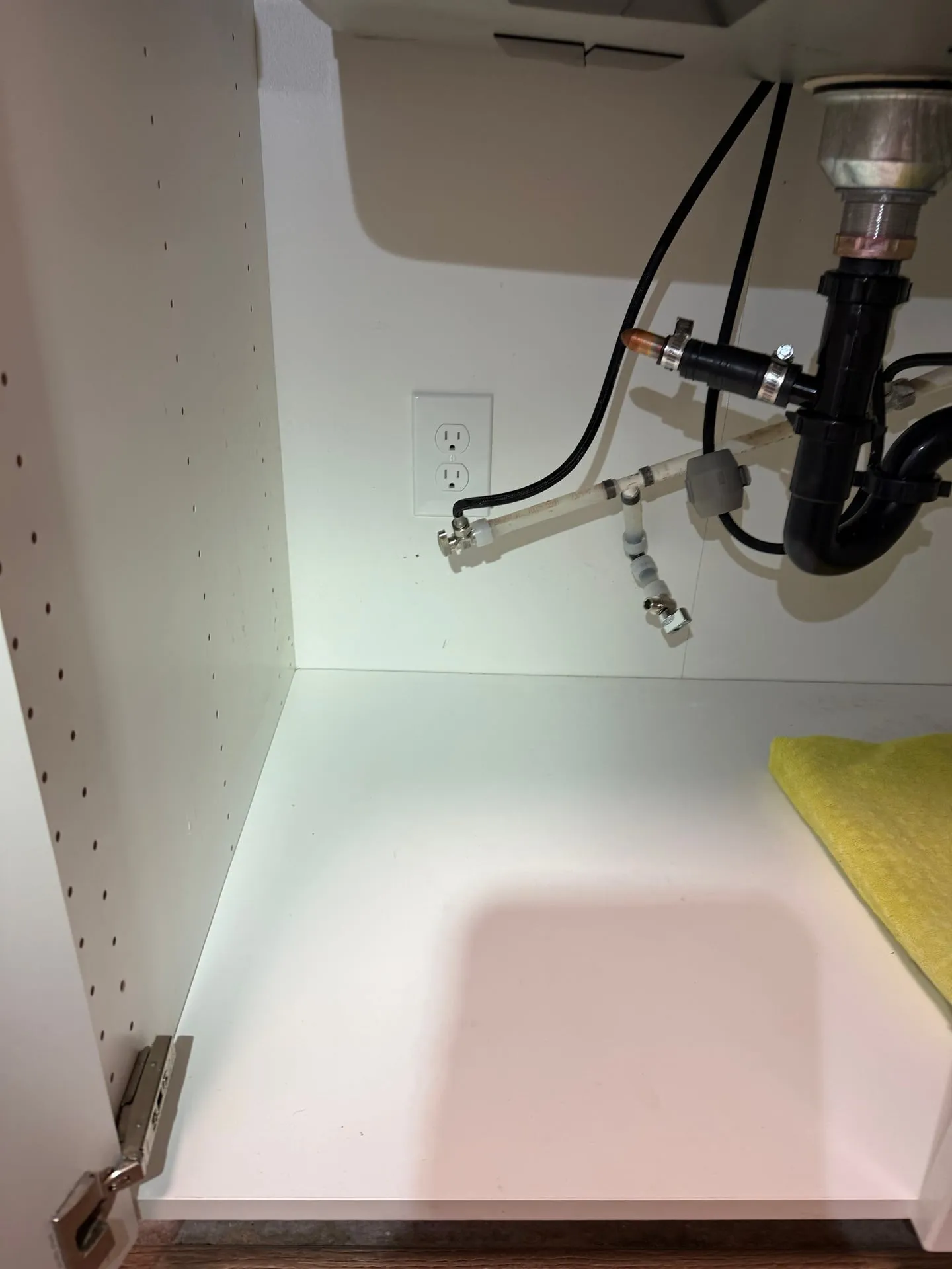 New receptacle installed inside the sink base cabinet of a downstairs kitchen in Vancouver WA to serve the dishwasher, with the drain and supply lines routed around it