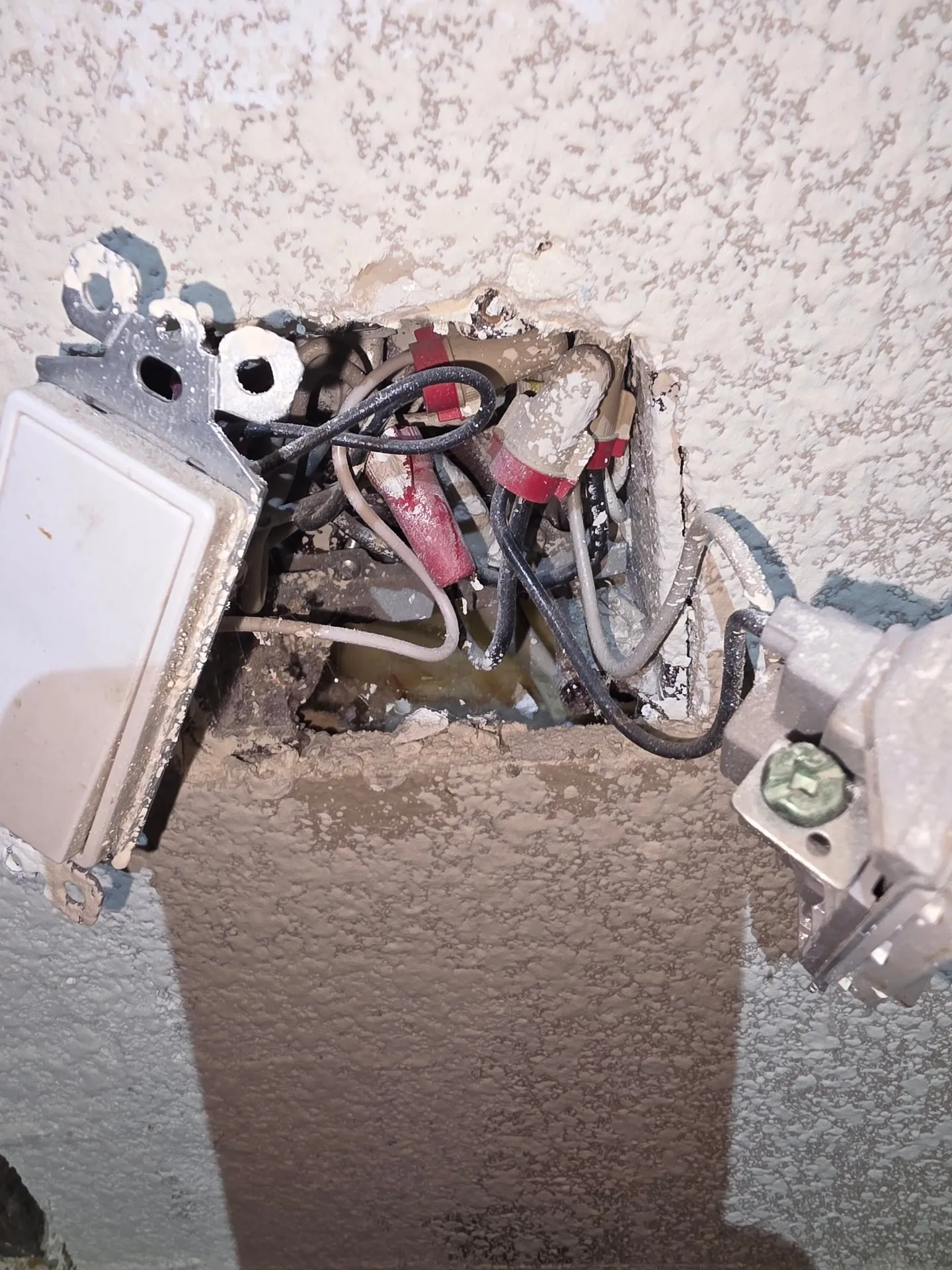 Wall opened at a switch location in a Vancouver WA home during a lighting retrofit, showing the existing conductors and box before the new switch layout was set