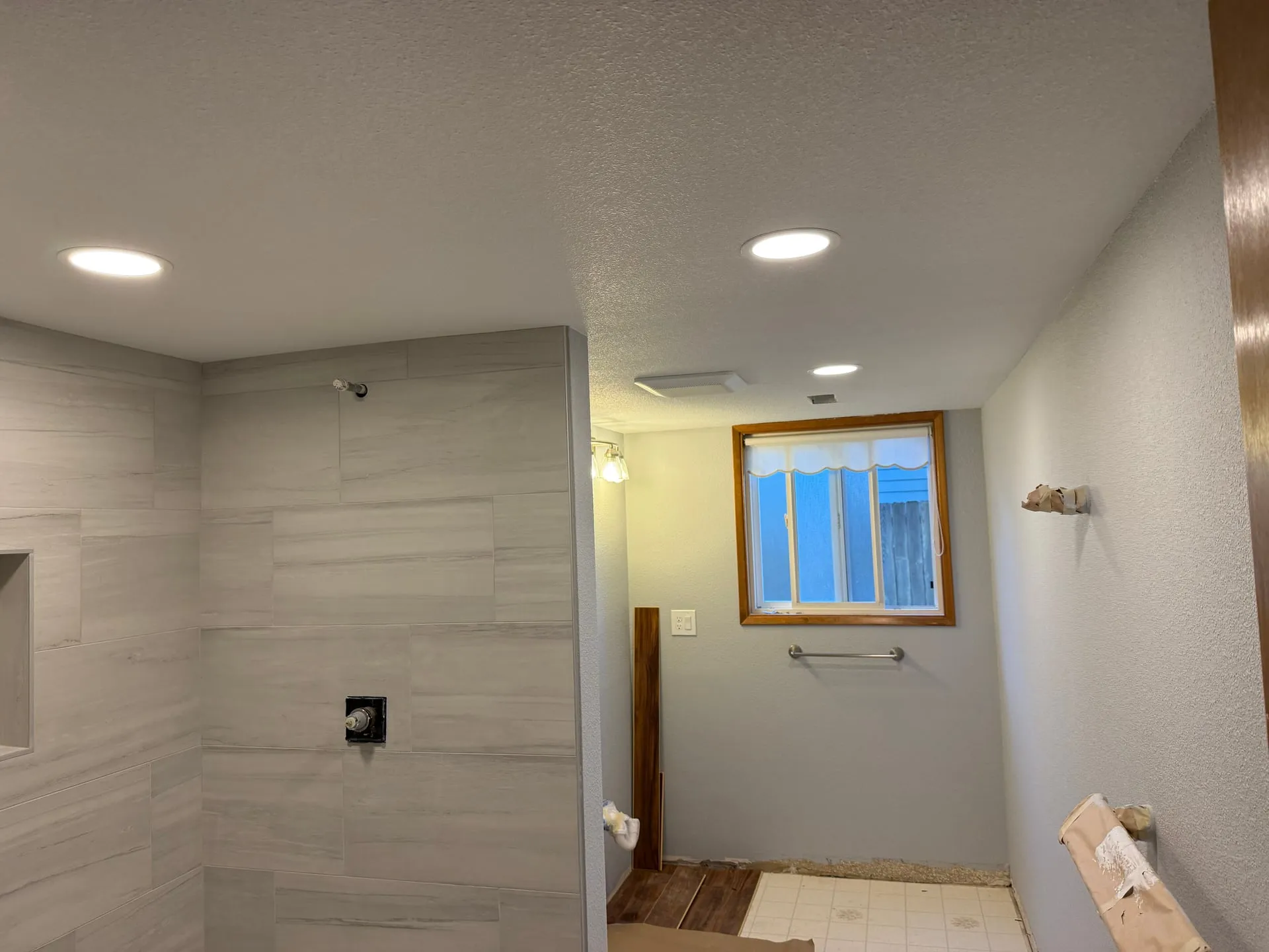 Finished bathroom in a Felida home in Vancouver WA with a tiled walk-in shower, recessed can lighting overhead and a vanity light beside the window