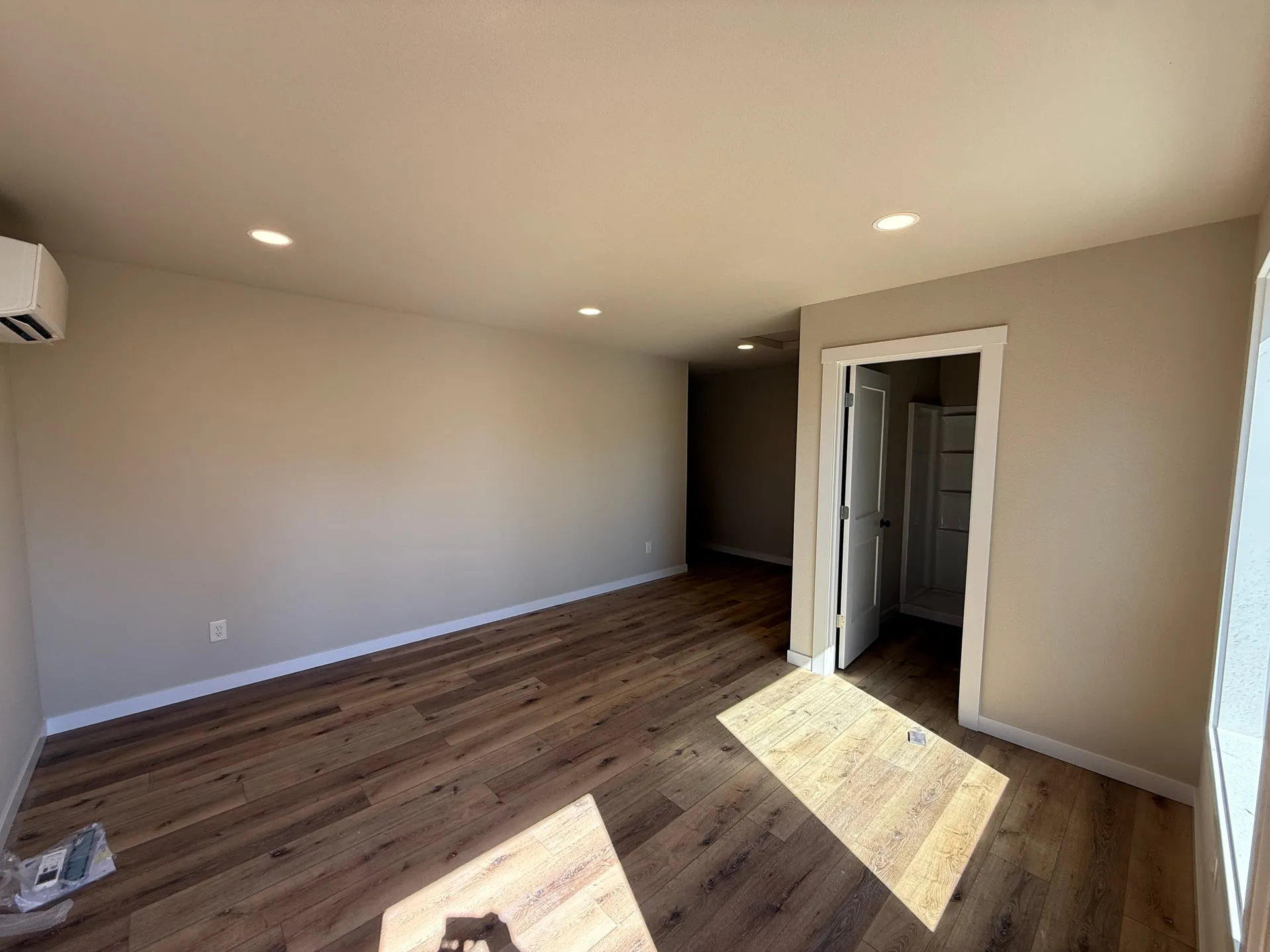 Finished room in a new shop building in Hazel Dell, Vancouver WA with a wall-mounted mini split head, recessed can lighting and wood-look flooring