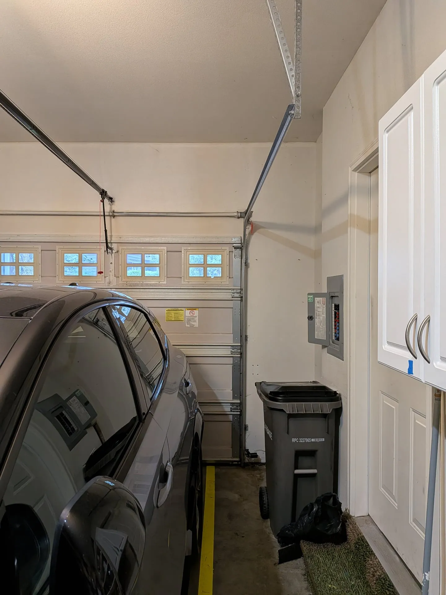 Narrow side of a Vancouver WA garage showing the electrical panel on the wall beside a white cabinet and a trash bin, next to a parked car