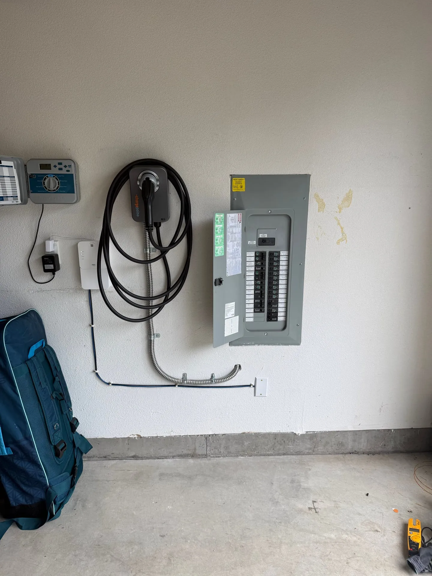 Wider view of the garage wall in a Camas WA home showing the ChargePoint charger and the electrical panel side by side with the conduit run between them