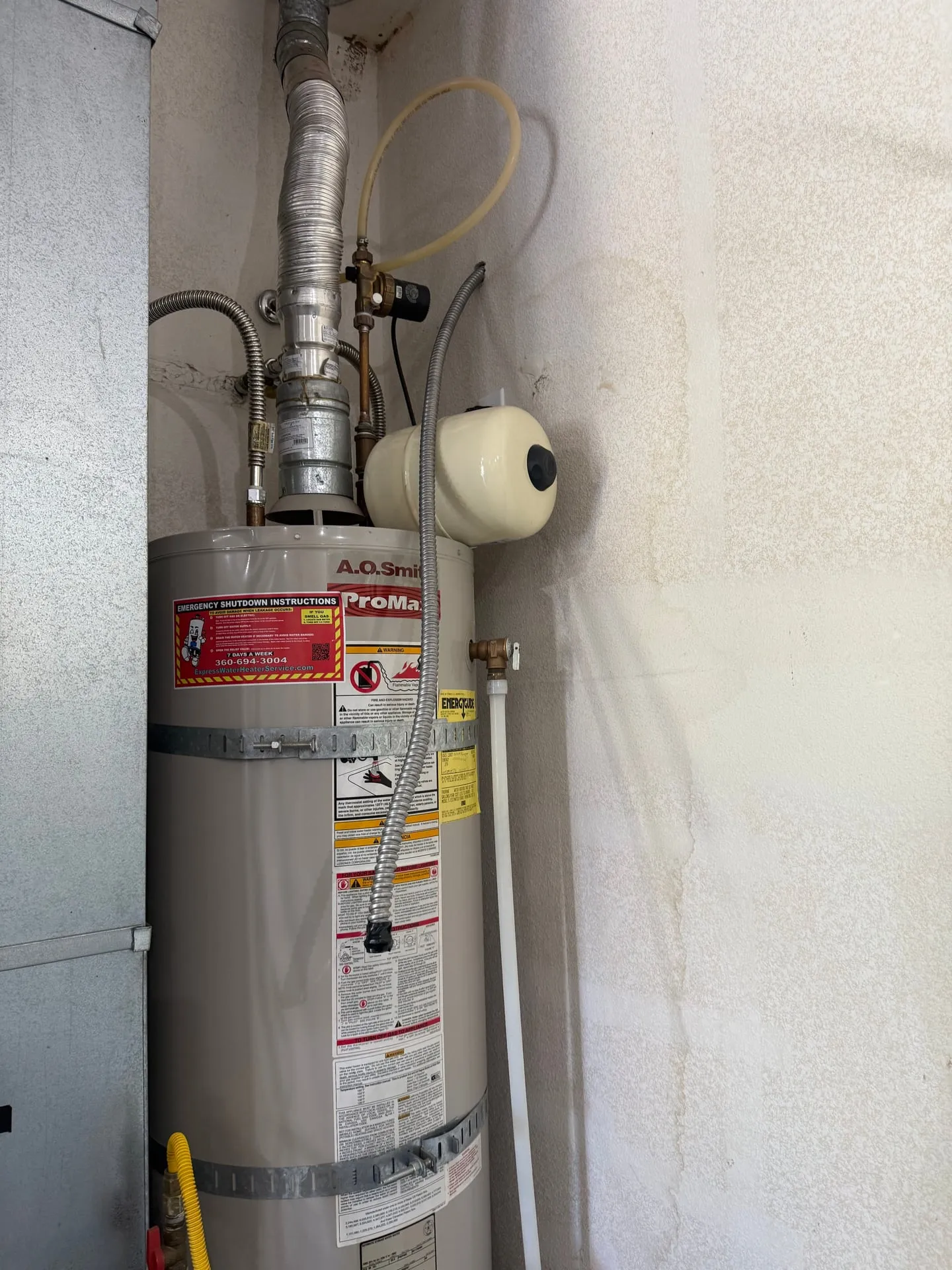 Existing gas water heater in the garage of a Vancouver WA home before the electric changeover, with flue and gas connections visible