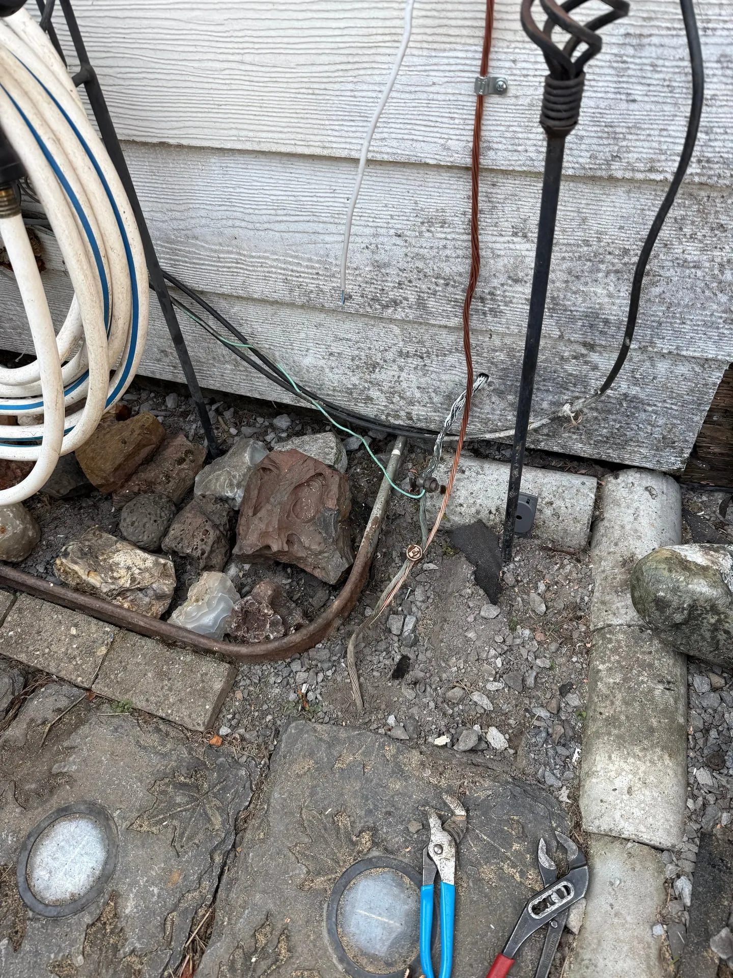 Grounding electrode conductor running down to a ground rod at grade beside the foundation of a Camas WA property, with the connection made among the landscape rock