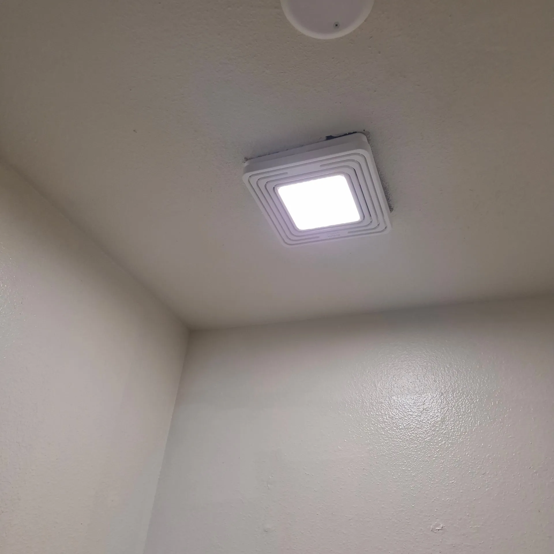 New bathroom exhaust fan and light combination unit installed and lit in the ceiling of a Vancouver WA rental, the surrounding ceiling clean after the circuit was restored