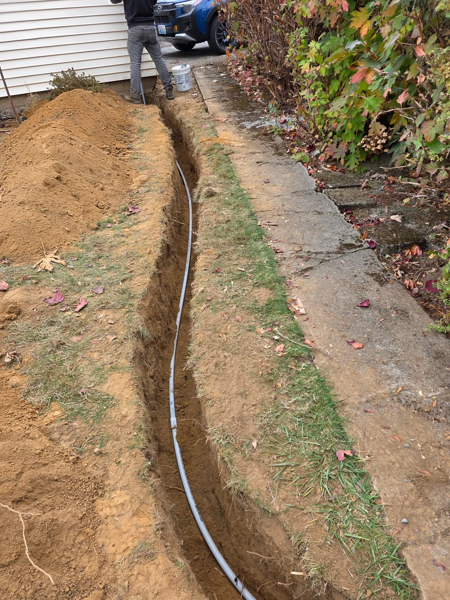 Open trench with gray PVC conduit running along a side yard from a house to a detached garage in Washougal WA