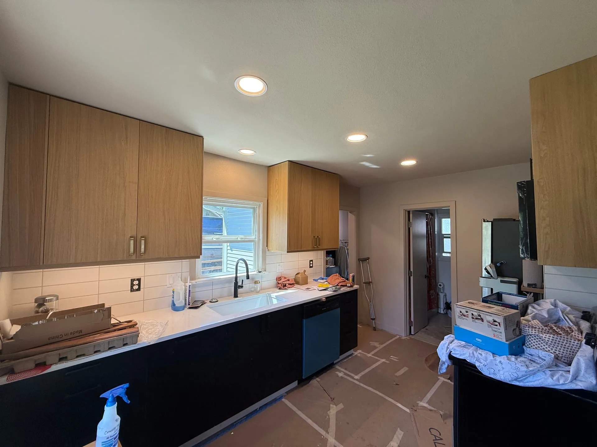 Rewired kitchen in a north Vancouver WA home with new recessed can lighting overhead, under-cabinet lighting along the counter, dark base cabinets and light wood uppers