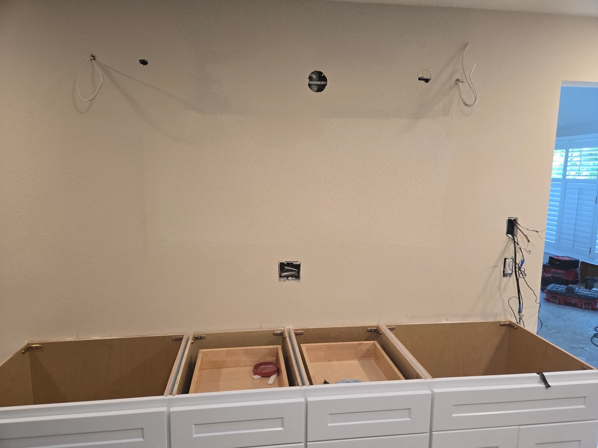 New double vanity cabinets set against a freshly textured wall in an Orchards Vancouver WA master bath remodel, with three electrical boxes roughed in above for vanity lighting and the center box positioned over the sink line