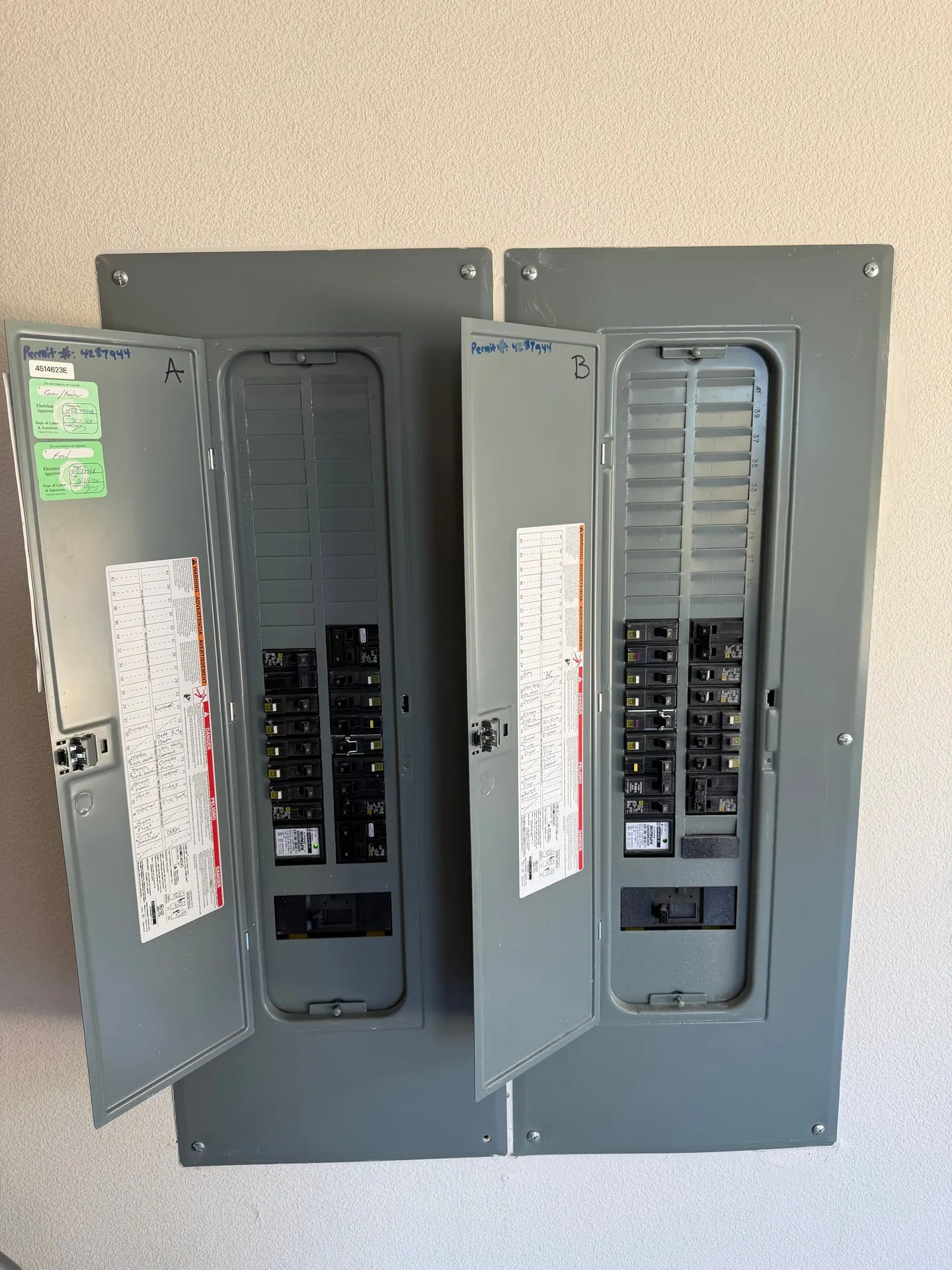 Two electrical panels open on a wall in a Battle Ground WA home showing the new 80-amp Homeline breaker landed to feed the pole barn