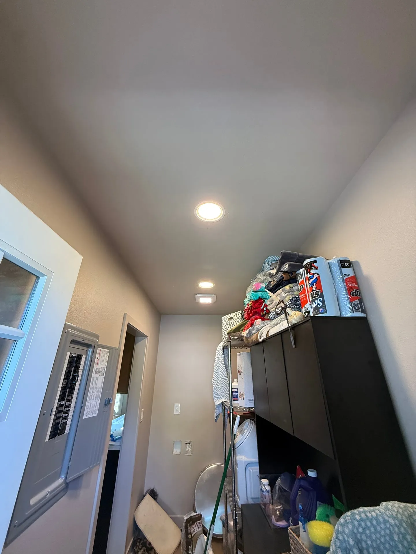 Laundry and utility area of a north Vancouver WA home with new recessed can lighting installed in the ceiling and the electrical panel visible on the wall