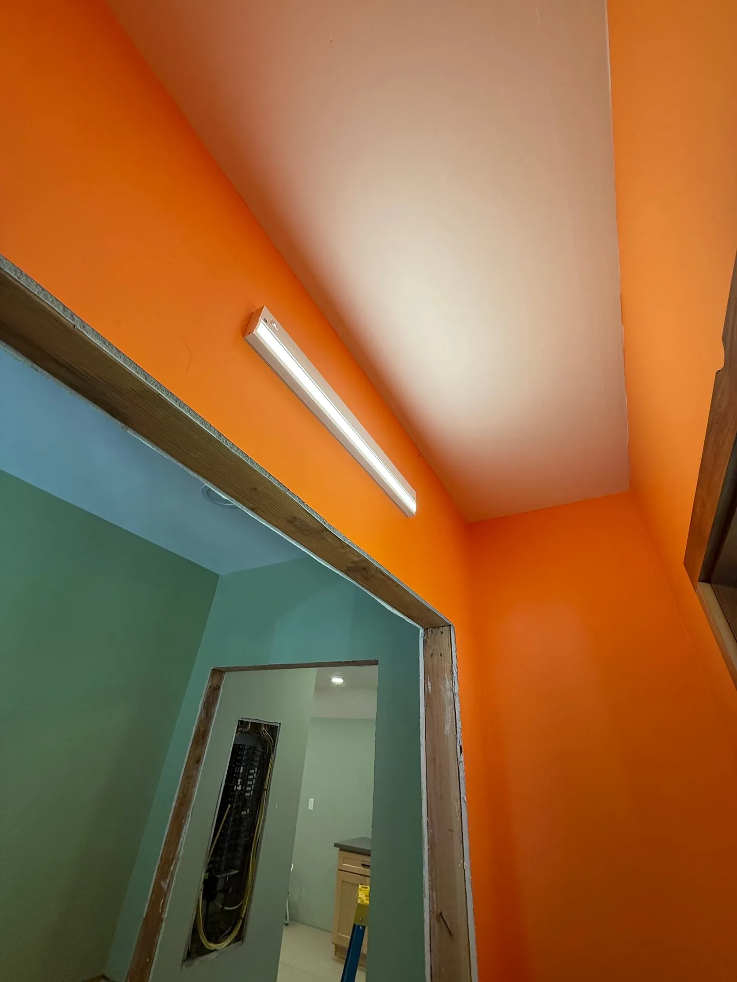 Linear LED fixture installed above a doorway in a Yacolt WA home remodel, with an orange feature wall and a teal room visible through the opening