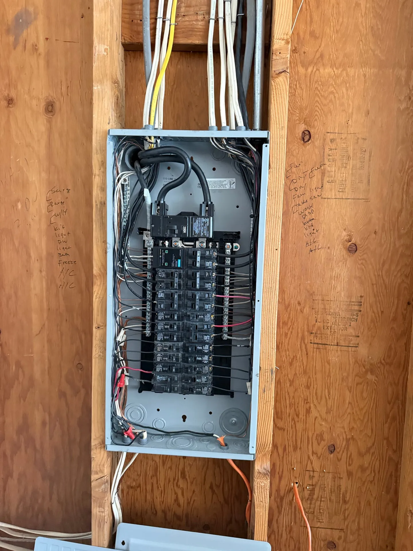 New 200-amp Siemens panel installed in the same garage stud bay in Vancouver WA, dead front off, showing the main breaker, a surge protective device and branch breakers with conductors landed