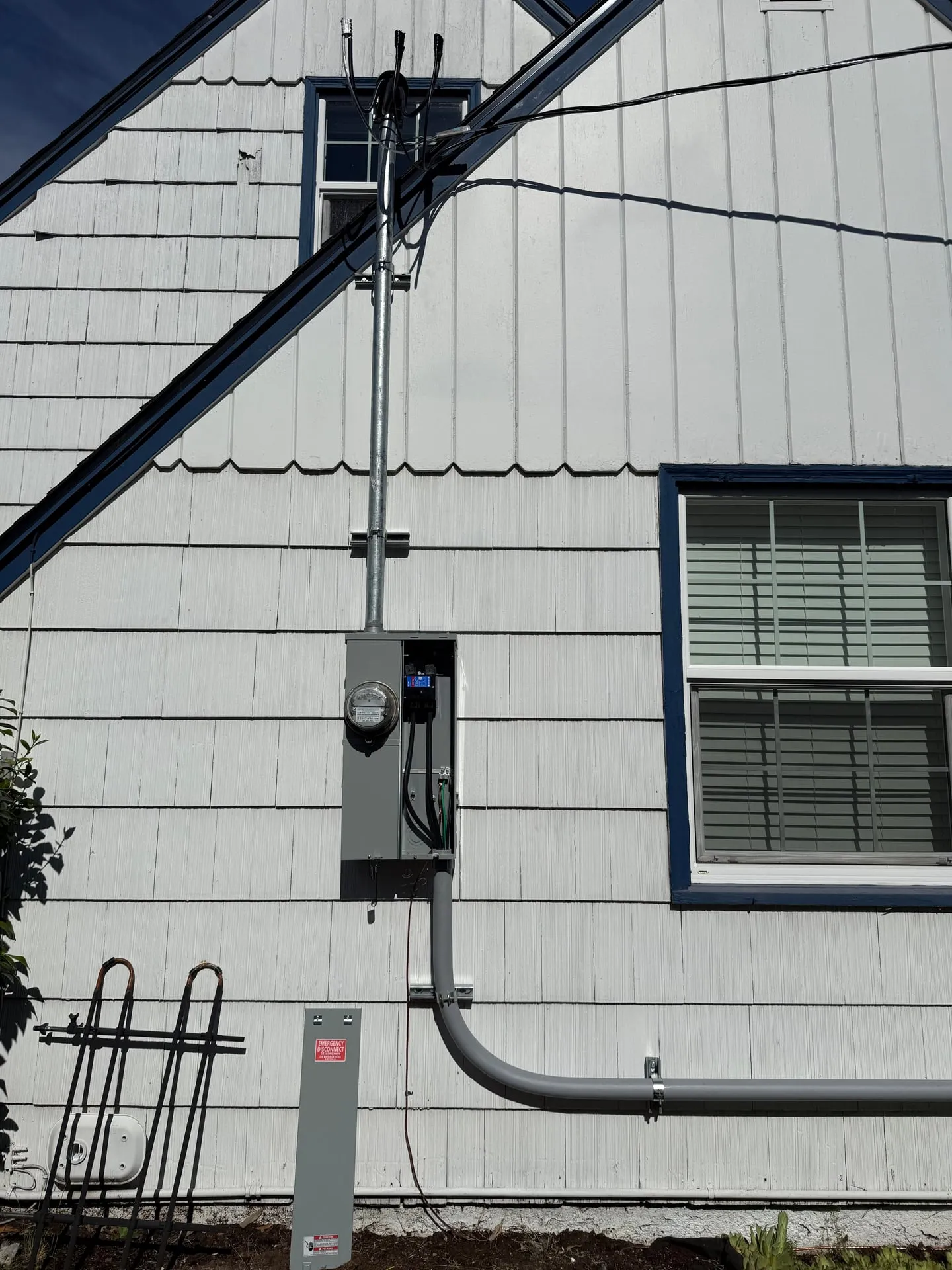 New service mast and 200-amp meter main on the exterior of a Vancouver WA home with the overhead service drop landing on the mast head above the roofline
