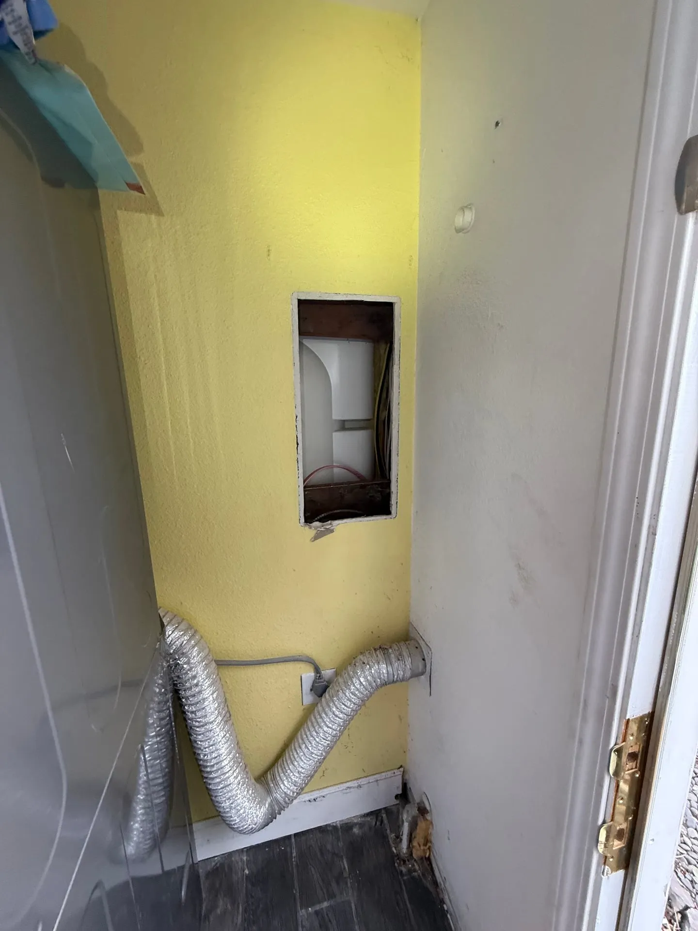 Laundry closet wall in a Vancouver WA home with a rectangular opening where the old electrical panel was removed, branch circuit cables visible inside the wall cavity