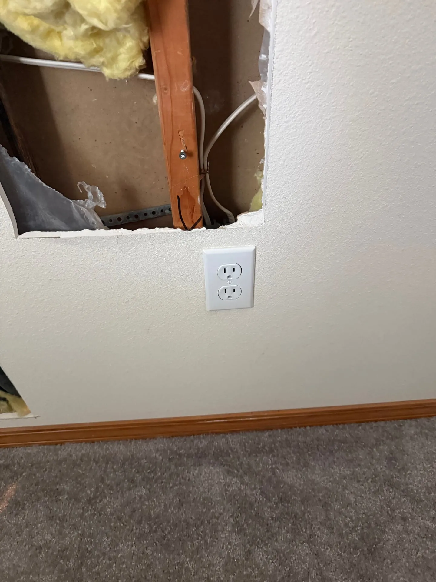 Opening cut in a bedroom wall above an outlet in an east Vancouver WA home, showing the stud and cables inside