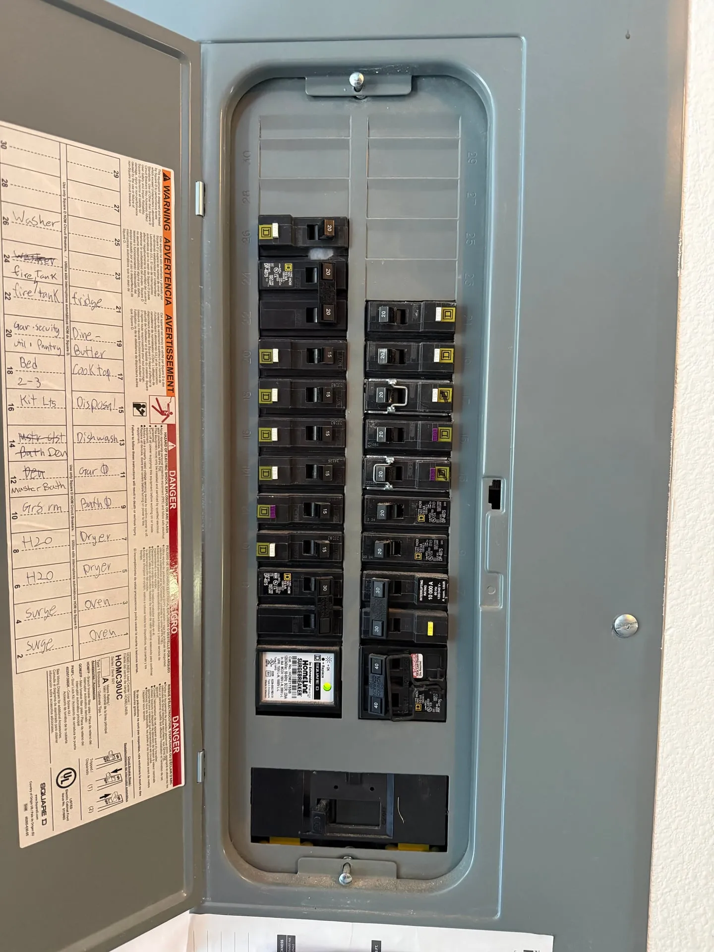 Square D Homeline electrical panel with the door open in a Ridgefield WA garage, showing a handwritten directory and a Homeline SurgeBreaker surge protector