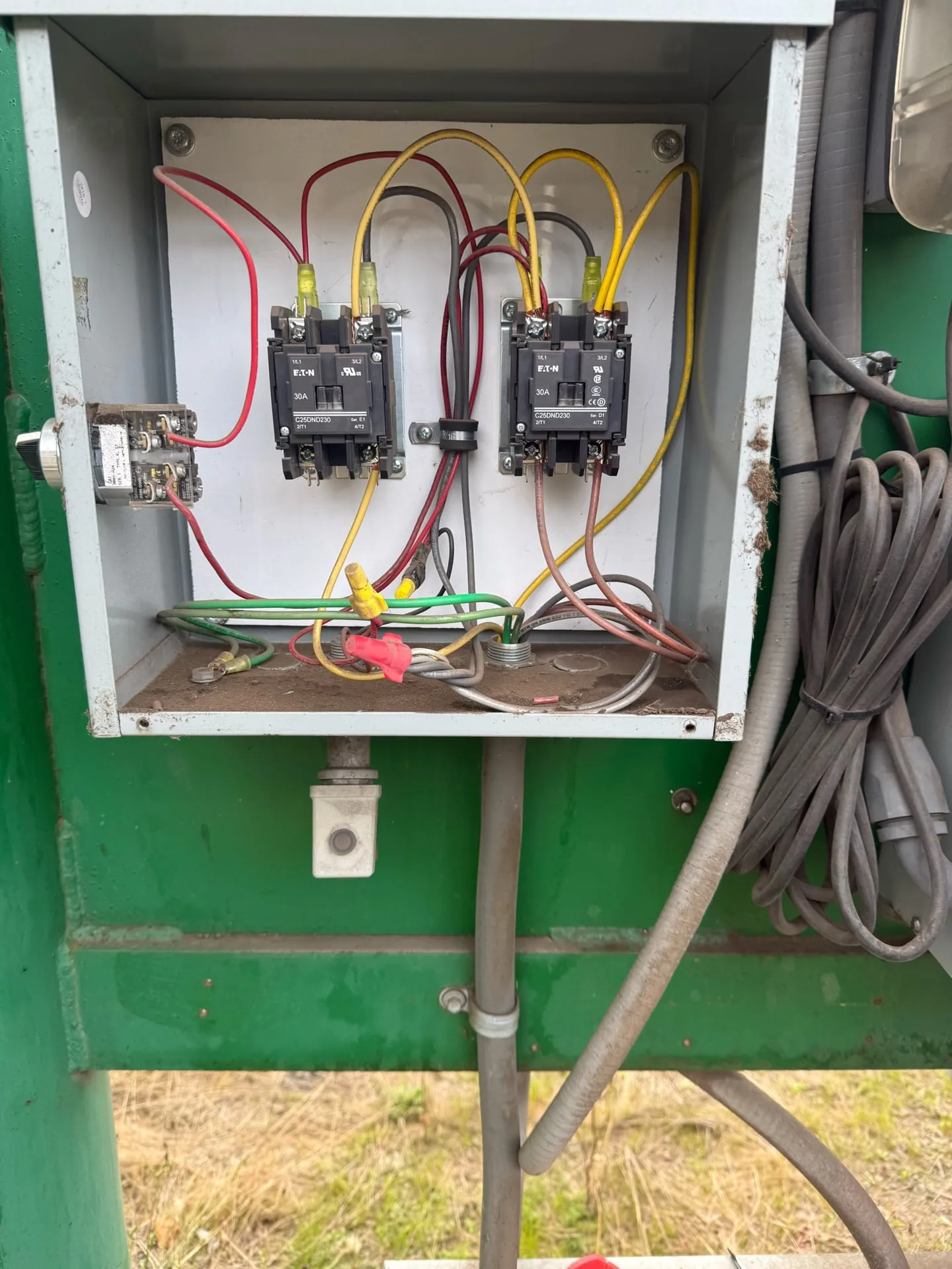 Open control box on a green post at a Longview WA commercial yard with two lighting contactors and a photocell control wired in