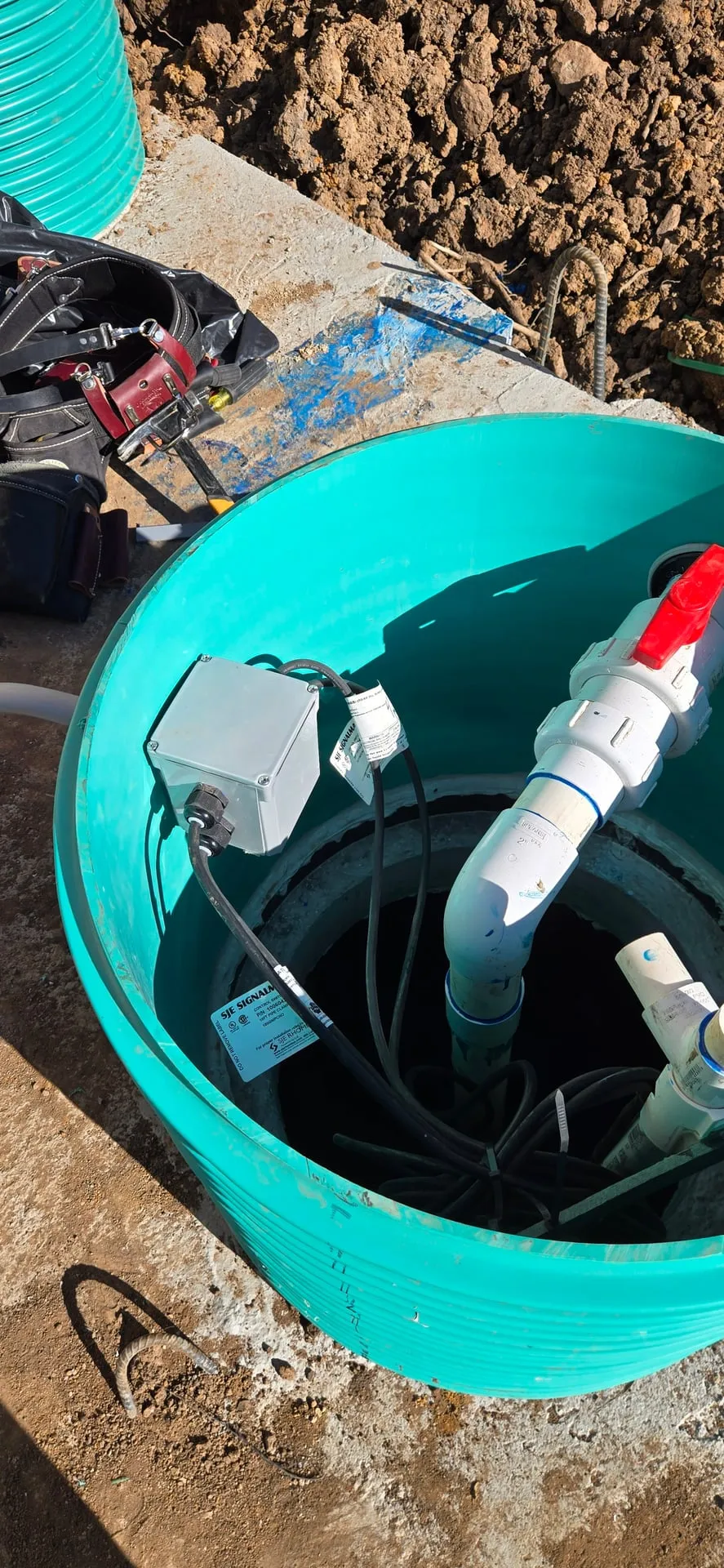 Green septic tank riser opened on a Kalama WA new-construction site with pump and float wiring landed in a junction box inside the riser