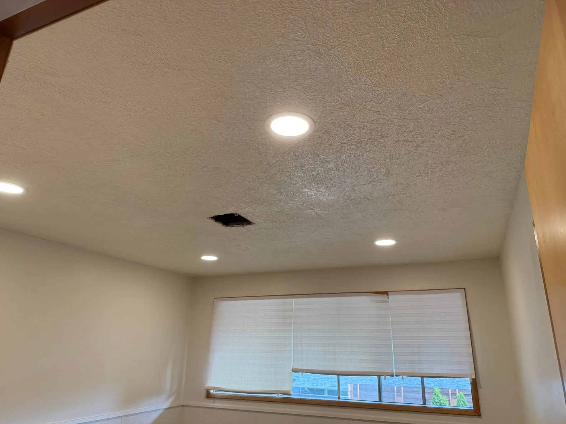 Second bedroom in a Hazel Dell home in Vancouver WA with new LED downlights installed in the ceiling and a window with blinds, floors protected during the work