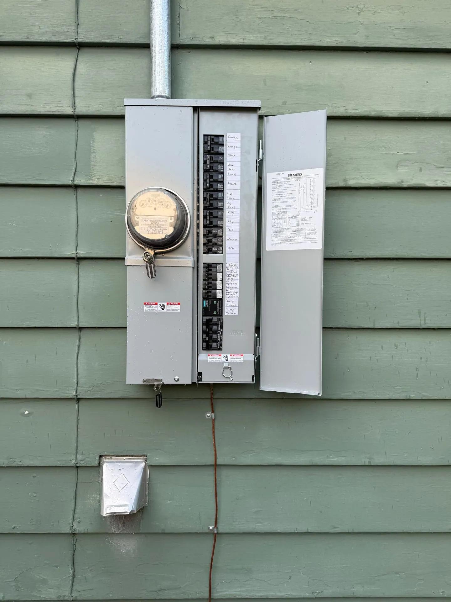 Siemens outdoor combination meter main open on a Vancouver WA home, showing the Clark Public Utilities meter, rows of breakers, a handwritten circuit directory and a whole-house surge protector near the bottom