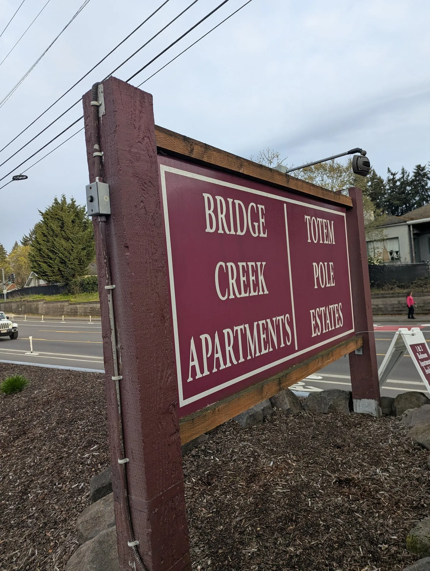 Close view of a low-voltage light fixture mounted on an arm above a monument sign at a Vancouver WA apartment community, angled down across the sign face