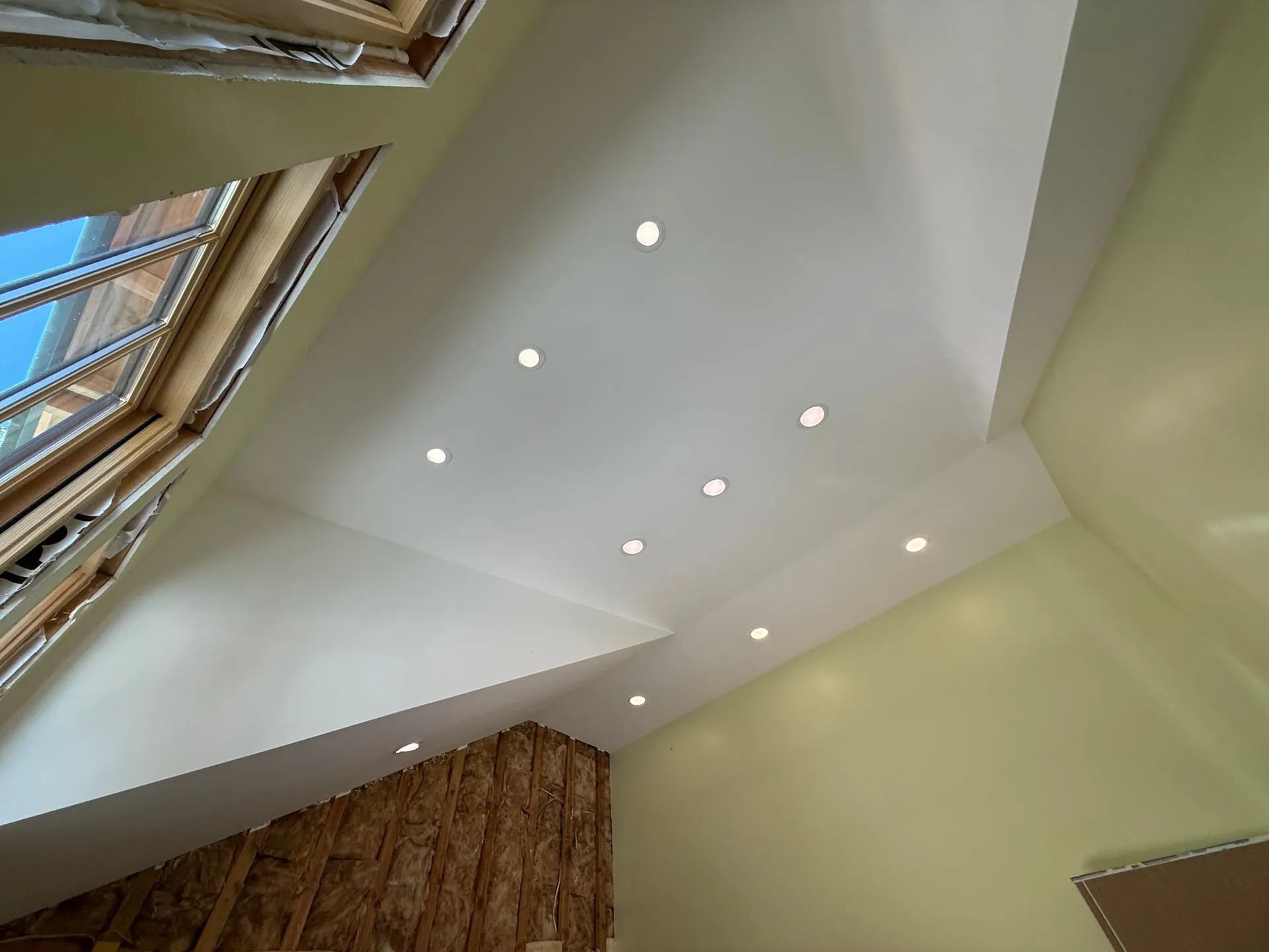 Vaulted ceiling in a Yacolt WA home remodel with recessed cans laid out along the slope and a skylight opening at the left, with framing still exposed at the lower wall