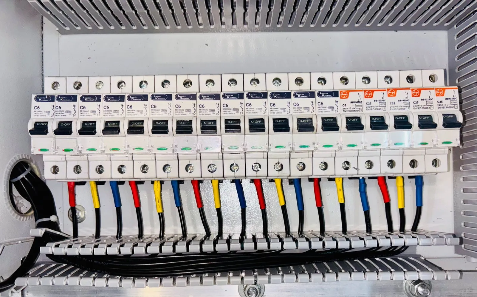 Close-up of a row of circuit breakers with color-coded wires connected underneath