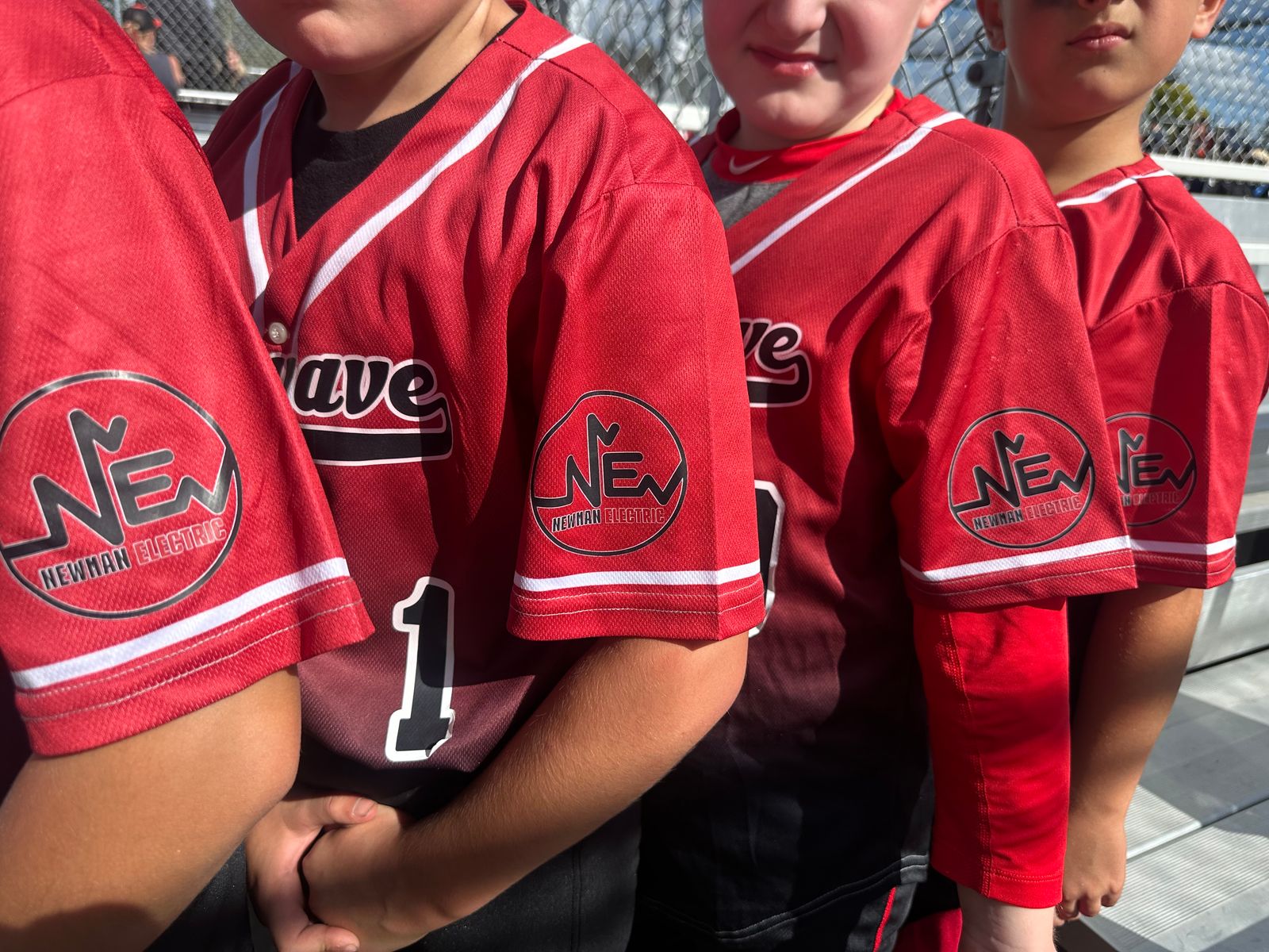 Kids wearing Newman Electric sponsored baseball jerseys at a local youth sports game
